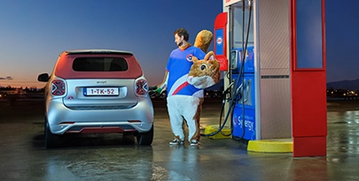 Man in een eekhoornpak met het hoofd naar het pak, benzine tanken voor zijn auto