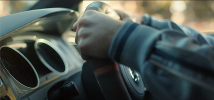 Een persoon in een auto met twee handen aan het stuur