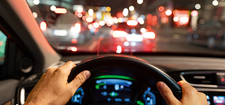 Een persoon in een auto die 's nachts rijdt met twee handen aan het stuur